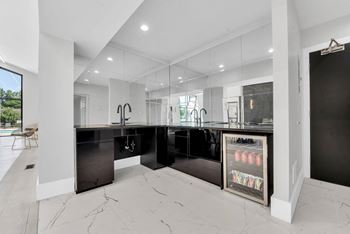 A modern kitchen with black cabinets and a marble floor.